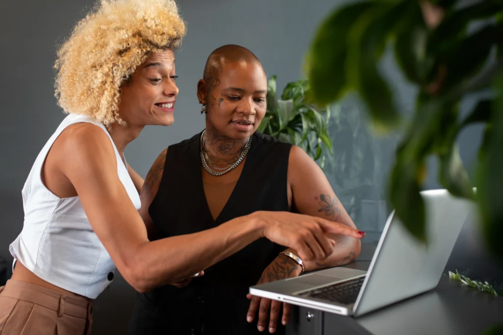Duas mulheres profissinais formadas em Marketing EaD discutindo tópicos de projeto no computador.