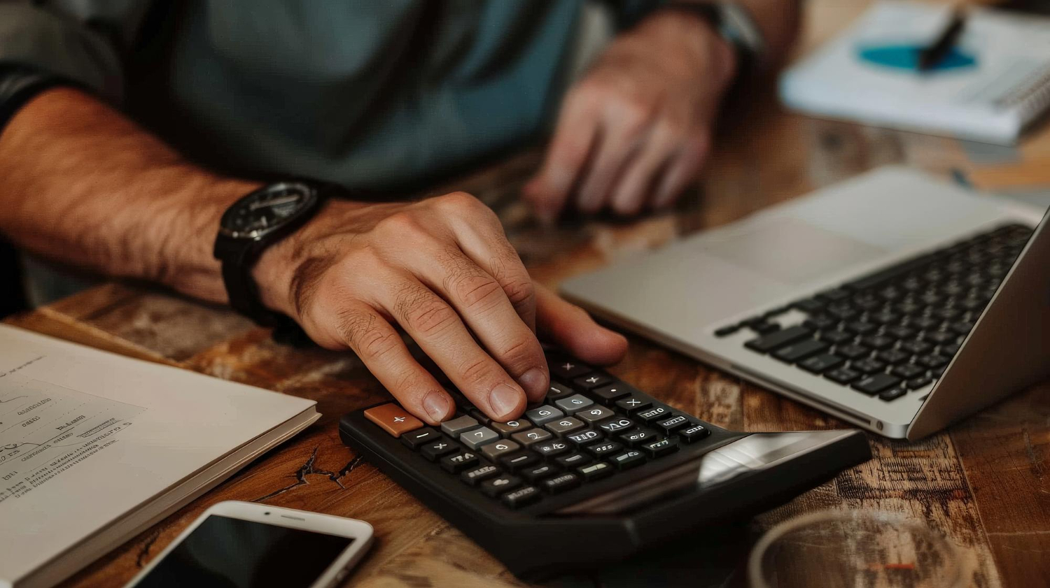Mãos de um profissional formado em ciências contábeis usando uma calculadora.