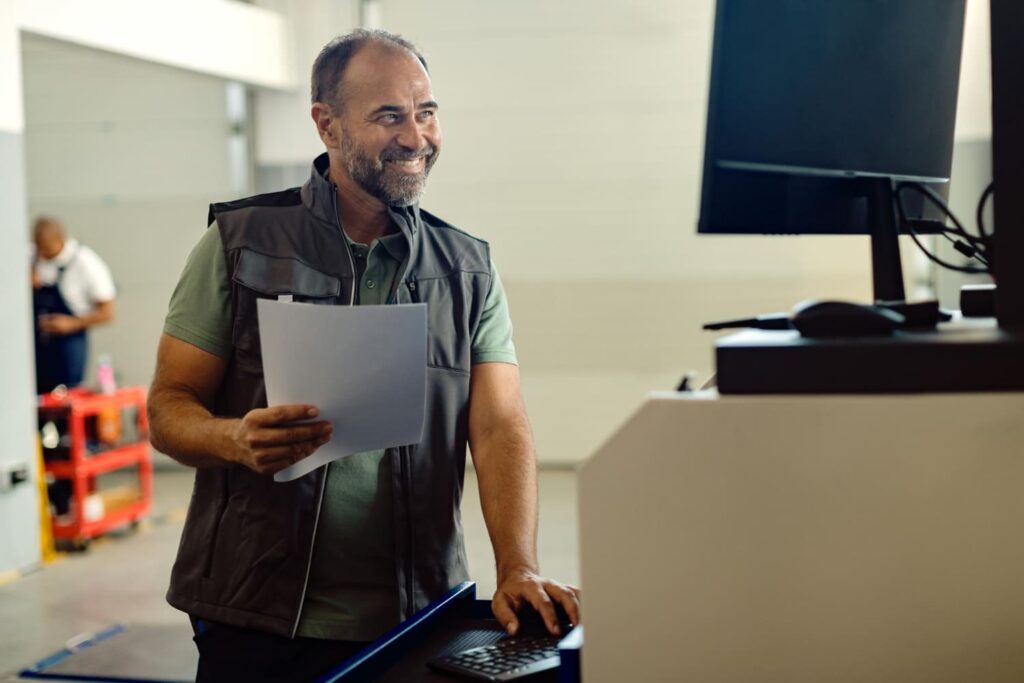 Profissional de mais de 40 anos trabalhando em um computador em uma oficina; entenda se é possível mudar de carreira aos 40 e iniciar uma faculdade depois de mais velho