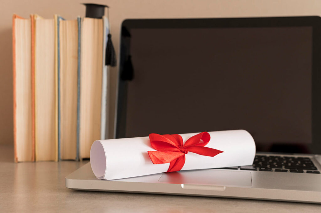 Diploma em cima de um computador, representando uma formação a distância (EAD); entenda se o diploma EAD vale para concurso